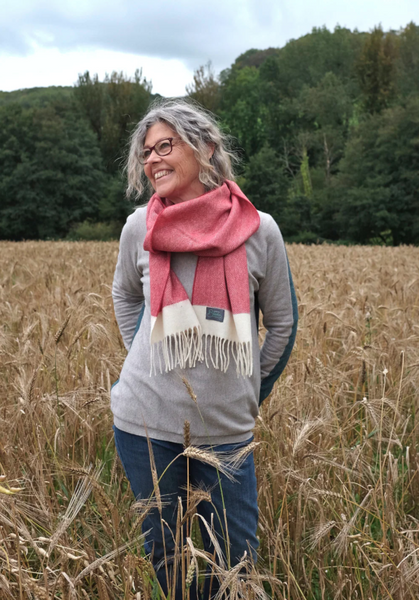 happy woman in a field wearing a red lambswool scarf from The British Blanket Company online