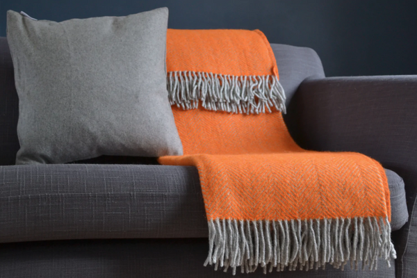 orange and grey herringbone wool blanket throw from The British Blanket Co on dark grey sofa