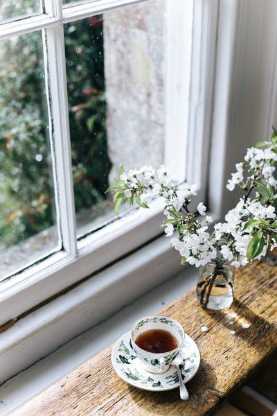 teacup on a windowsill with a vase of white flowers photo abbie melle