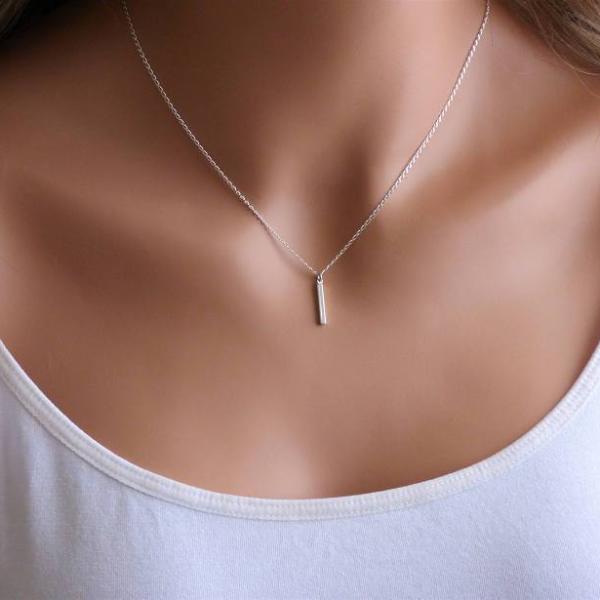 A woman is wearing a small bar necklace in Sterling Silver.