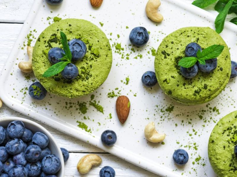 Matcha cupcakes with blueberries on white tray decorated with nuts