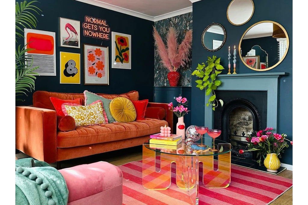 A dopamine decor style lounge with stripey rug, dark blue walls and multicoloured pictured and cushions. Image credit : Rachel Verney @the_shoestring_home