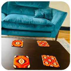 customer photo of orange 70s op art coasters on a coffee table in front of a blue sofa