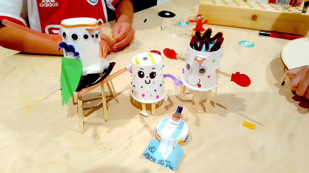 Image of three paper cup robots and one cup lid robot decorated with recyclable materials