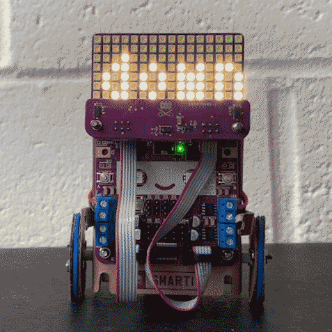 Looping video of a Smartibot with an LED matrix and sensor board attached. A hand waves in front of it and the direction of movement is written on the LED martix 