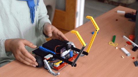 A GIF of a girl rotating a robot made from LEGO