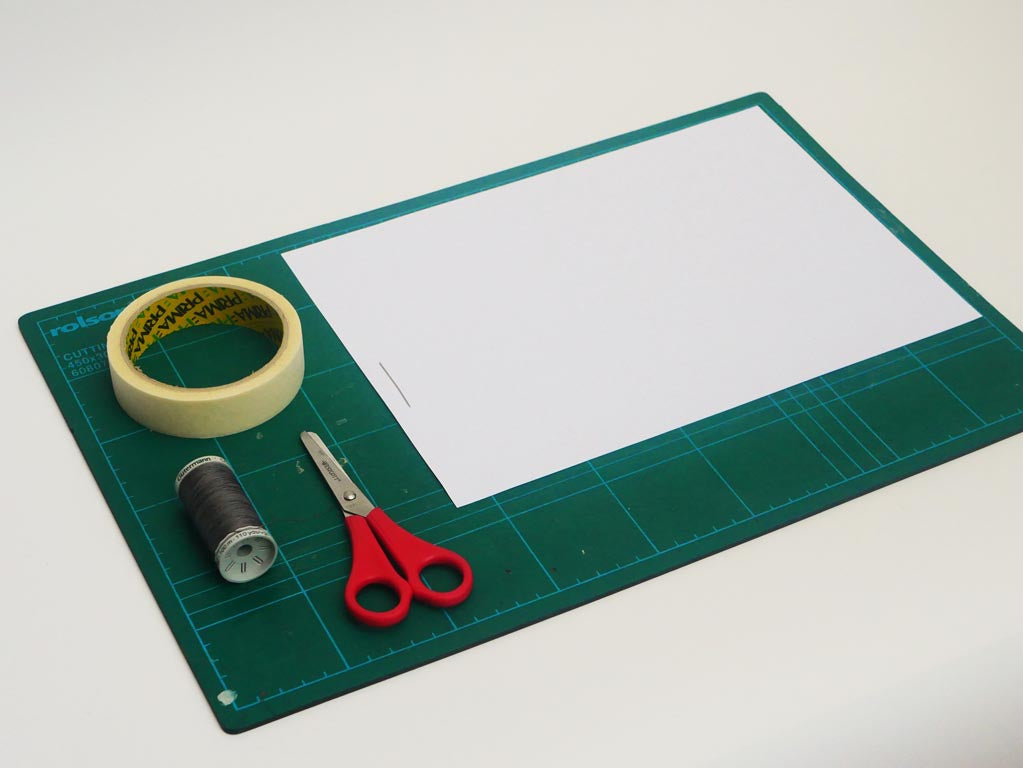 Image shows equipment for the cradle laid on the cutting mat, including scissors, Sellotape, needle, string and paper.