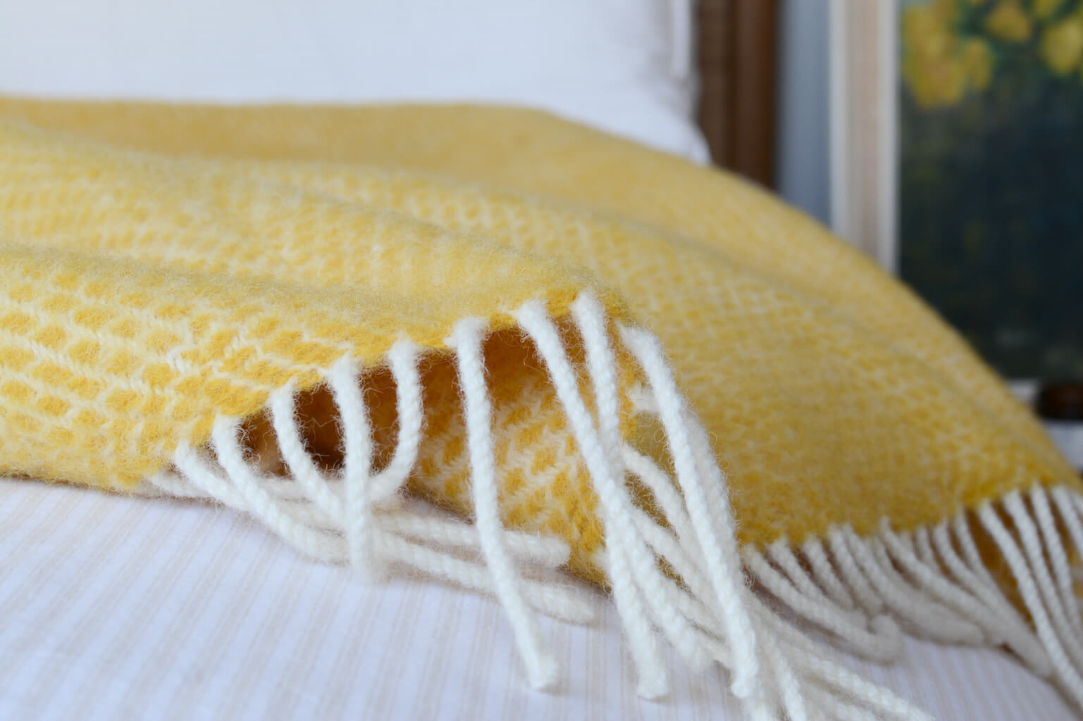 yellow blanket with ivory fringe, on top of a bed