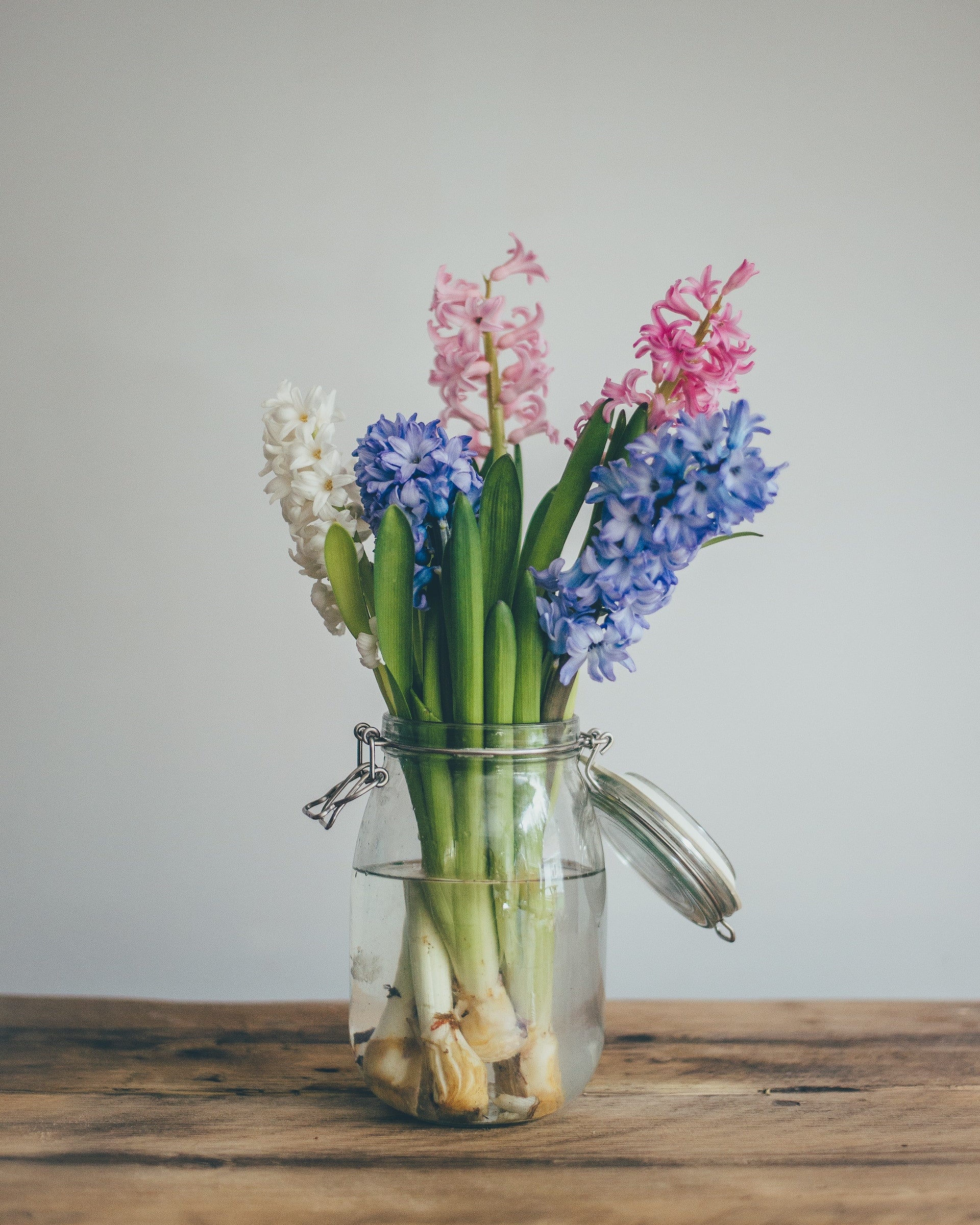 A selection of Spring blooms in an open kilner jar, on top of a wooden table.