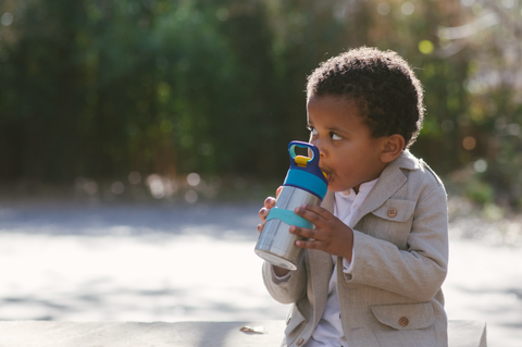 young boy drinking from Thermos straw bottle with personalized name label