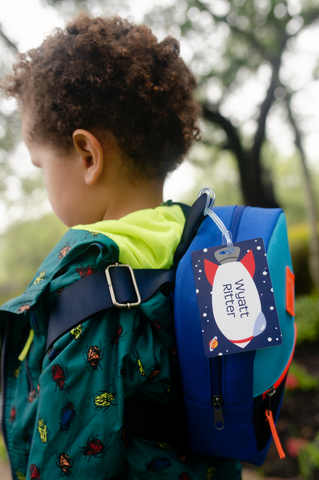 young boy with backpack and personalized bag tag outerspace