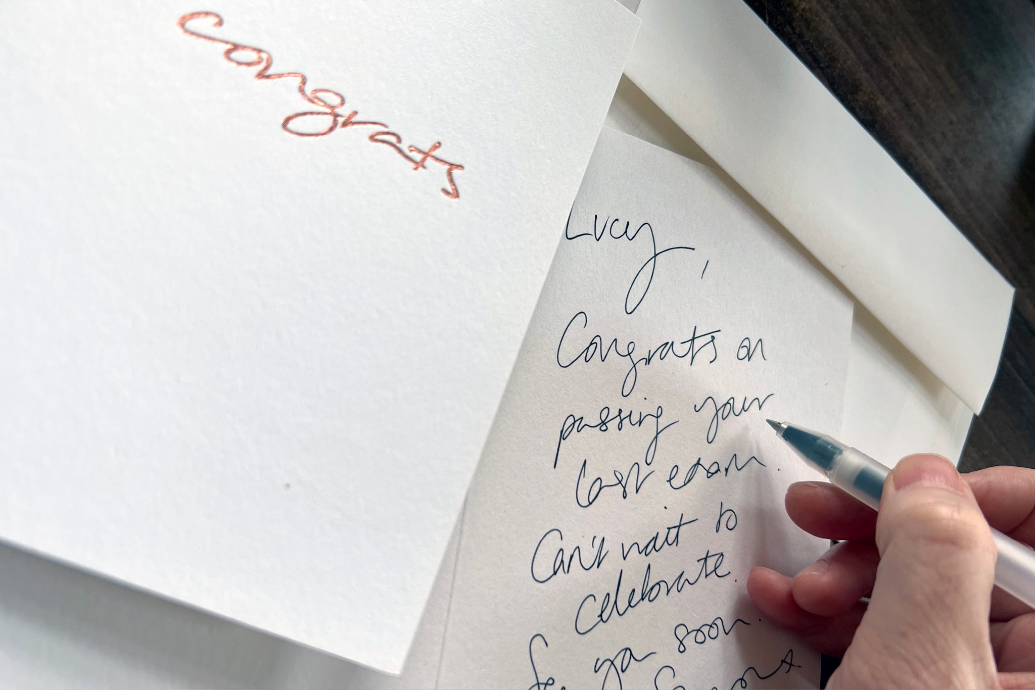 handwriting a note inside a congrats greeting card 