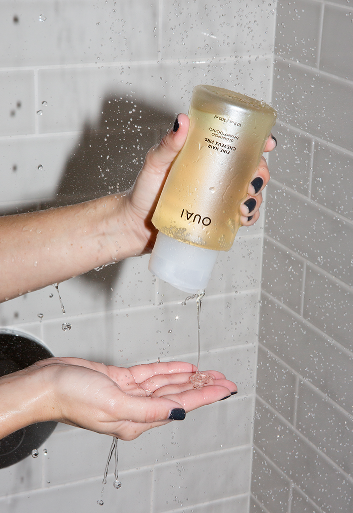 Woman Squeezing Bottle Of Volumizing Shampoo For Fine Hair In Shower