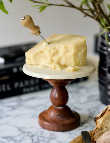 hunk of parmesan reggiano on walnut and porcelain cupcake stand