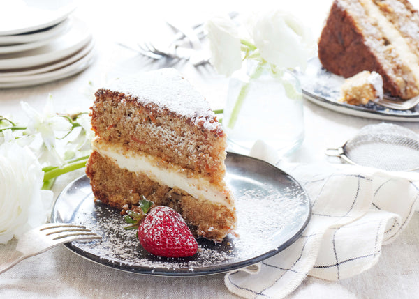 Vegan layer cake and strawberry on bare salad plate sprinkled with confectioner's sugar