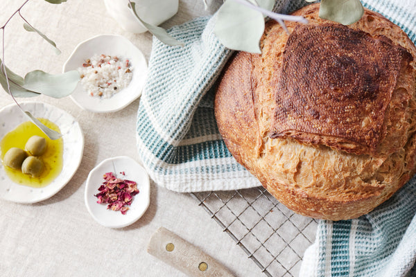 loaf of fresh backed sourdough bread with tiny bowls filled with olive oil and salts