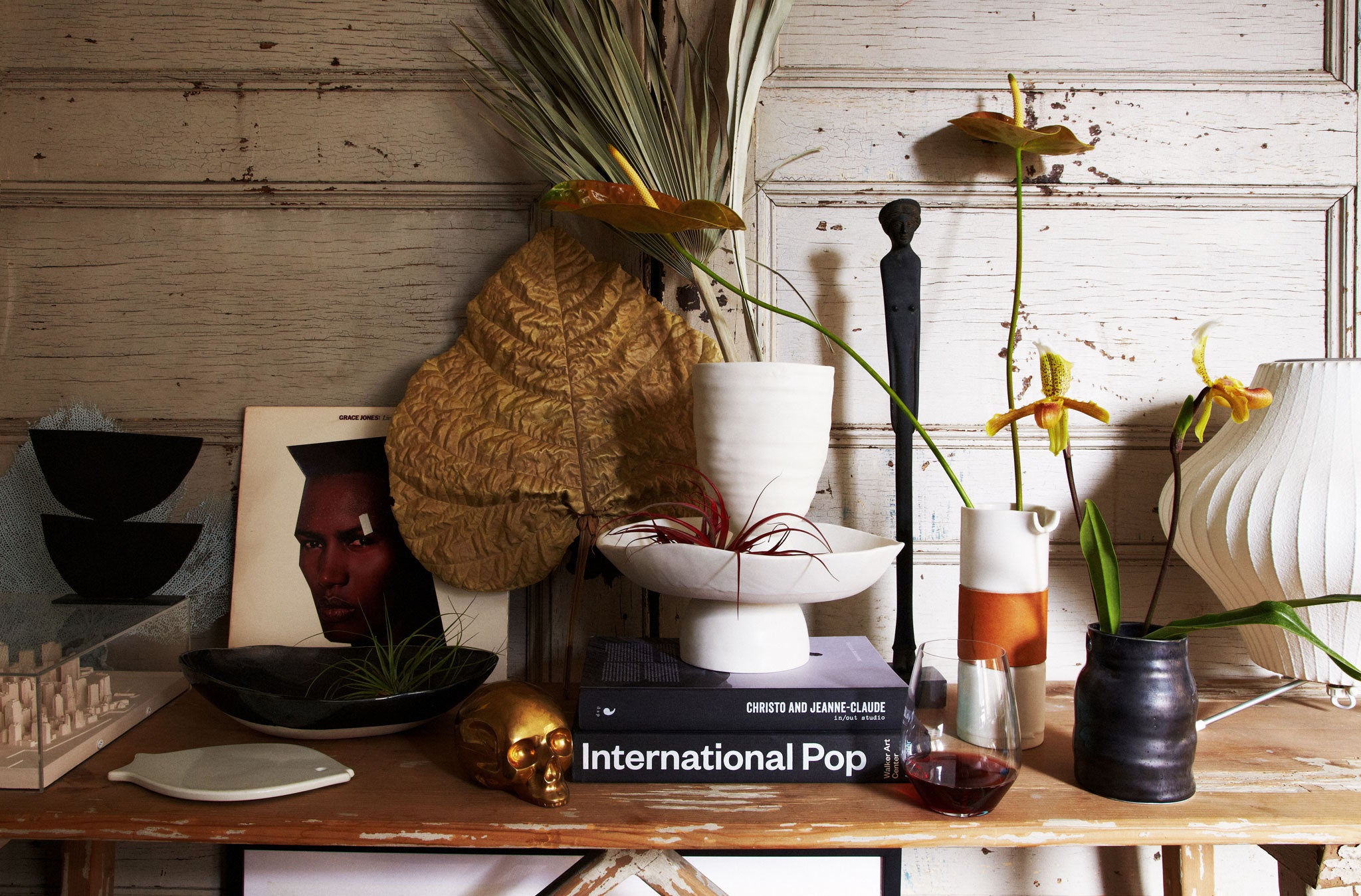 DBO HOME ceramic vases and bowls on wooden table with decorative leaves, flowers, books and art as styled by Marcus Hay