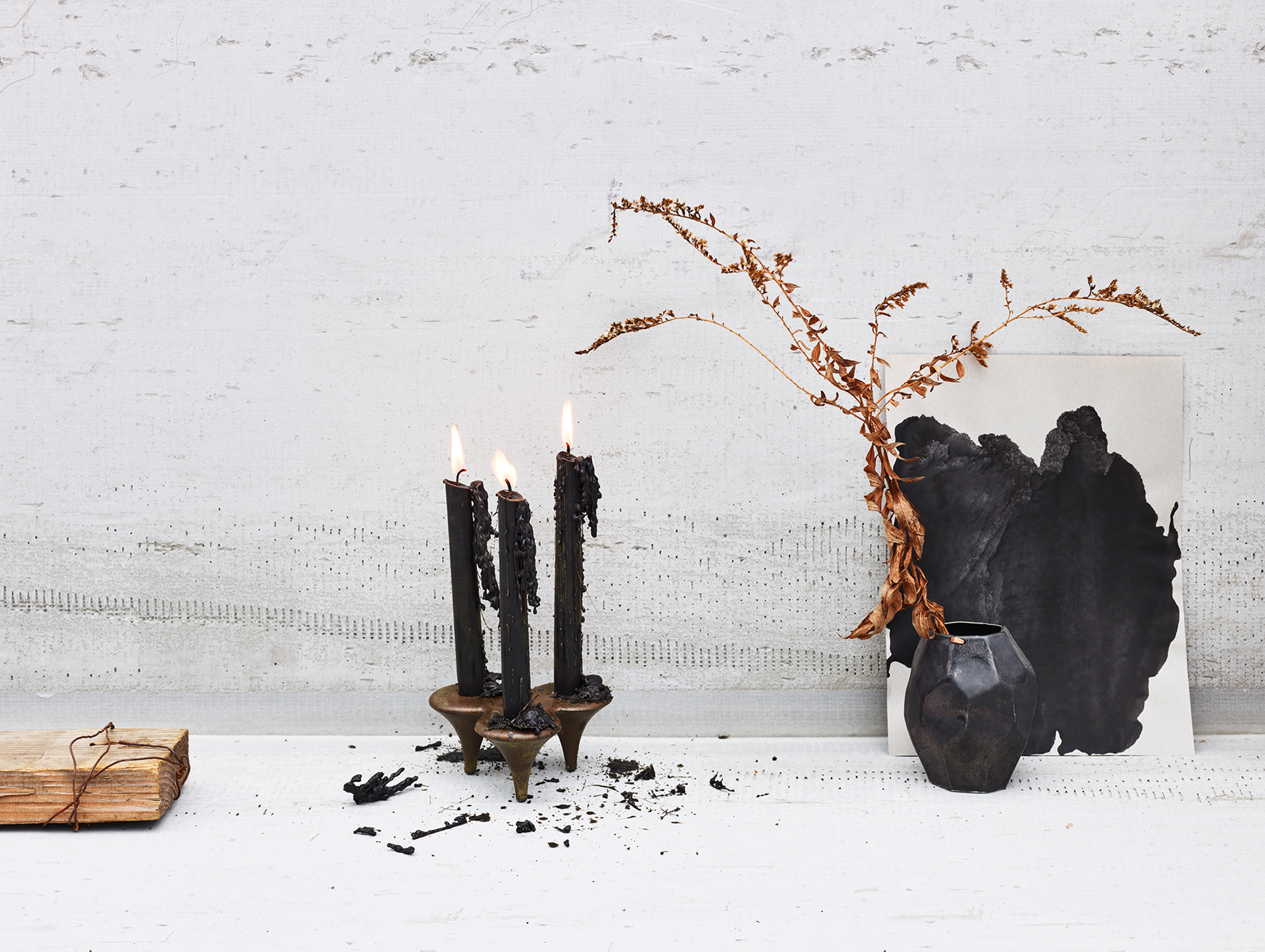 Bronze Candlesticks with black candle tapers and black ceramic vase on concrete background