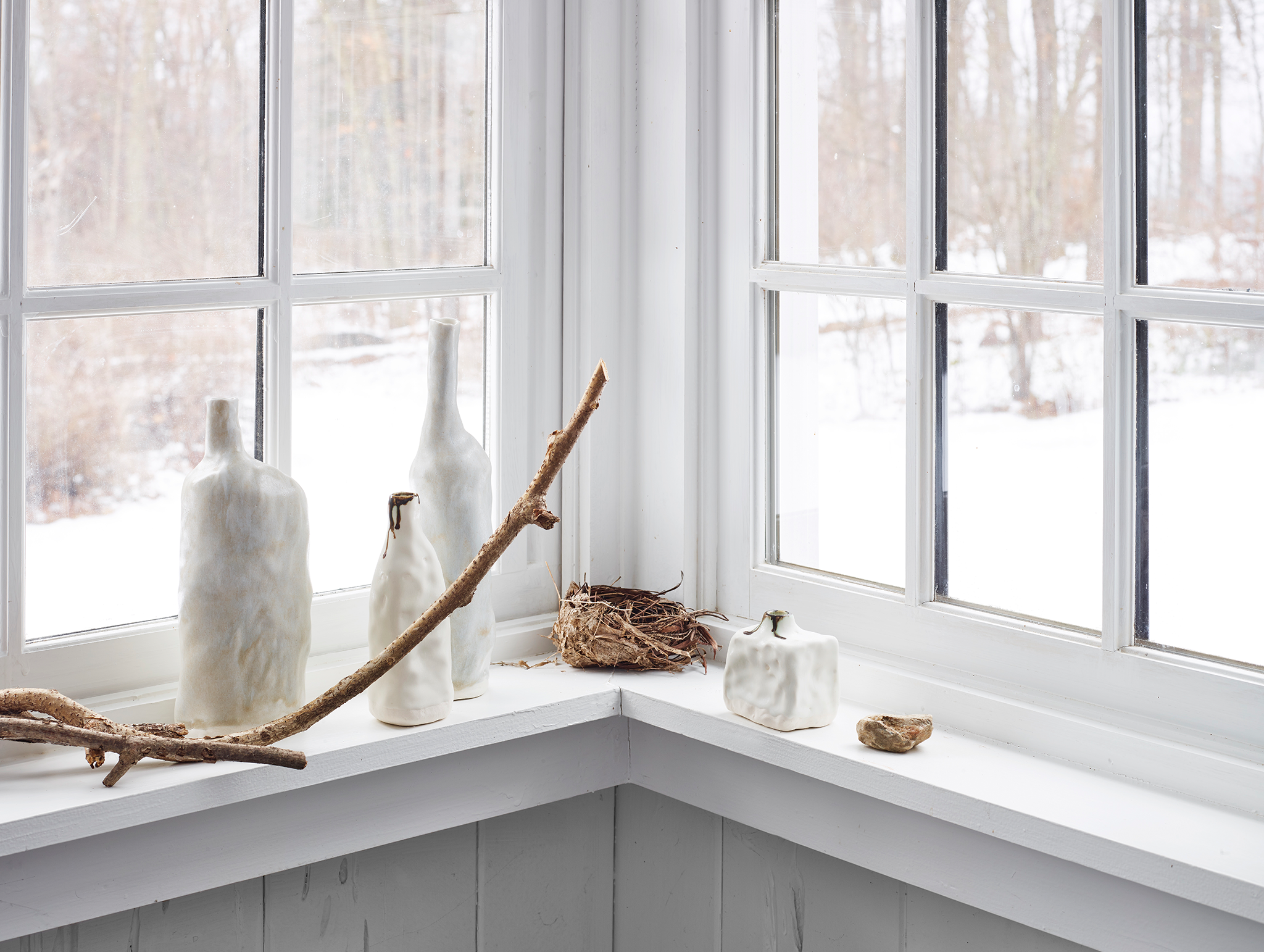 White artisan porcelain pitchers on winter windowsill with snowy background