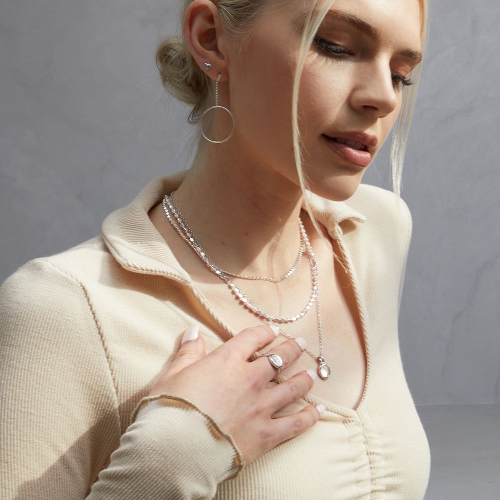 A woman wearing the FIYAH silver and clear quartz adjustable ring and necklace from the Healing Stone collection