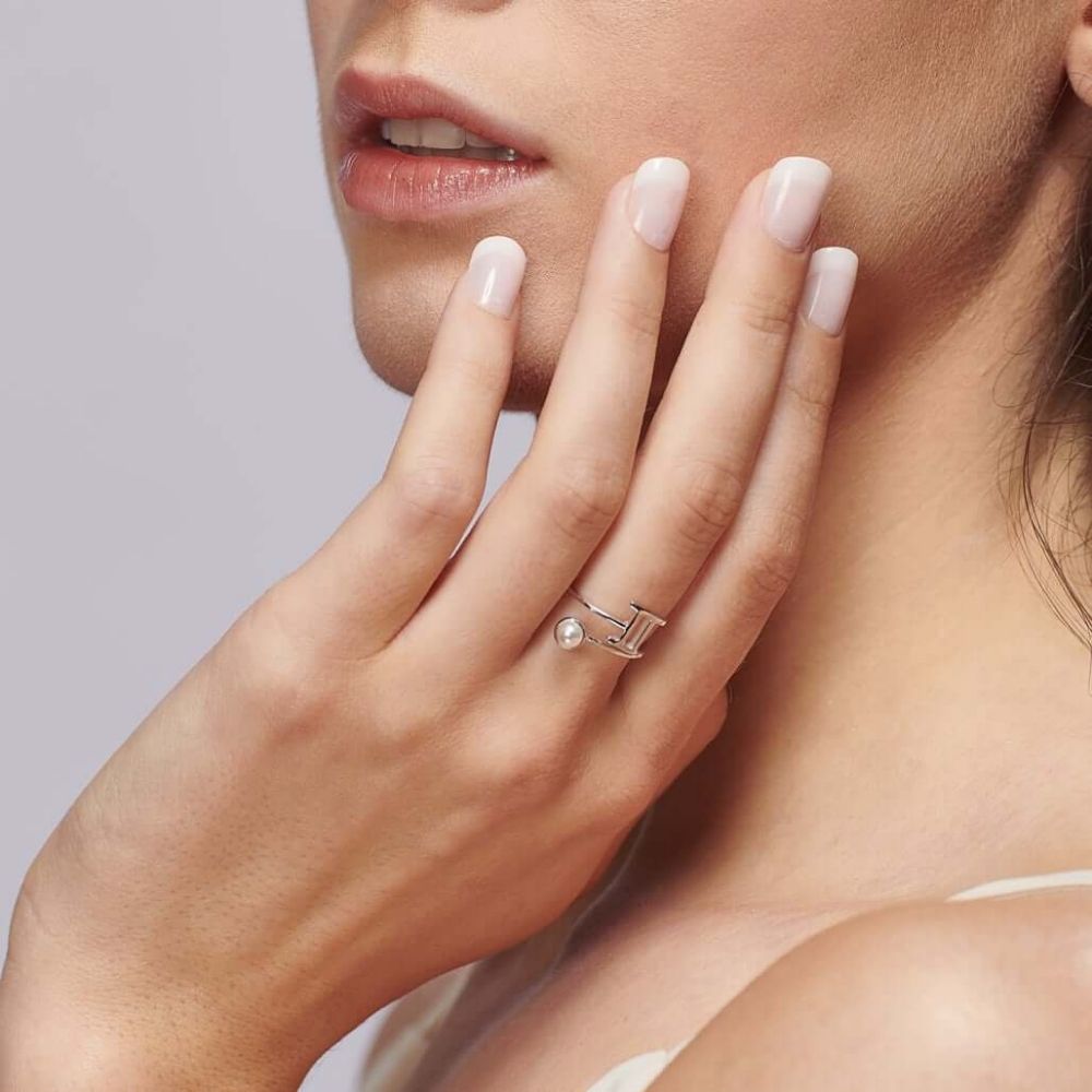 A woman wearing the silver Gemini Zodiac Star Sign ring from the FIYAH zodiac collection - set with a white Swarovski crystal lookalike pearl