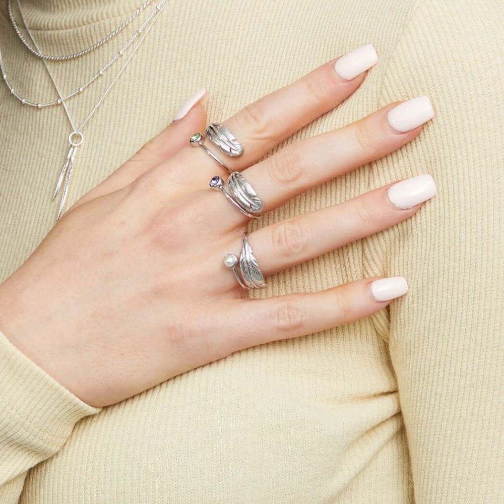 A woman wearing silver and crystal set birthstone rings from the FIYAH birthstone collection including the June birthstone ring