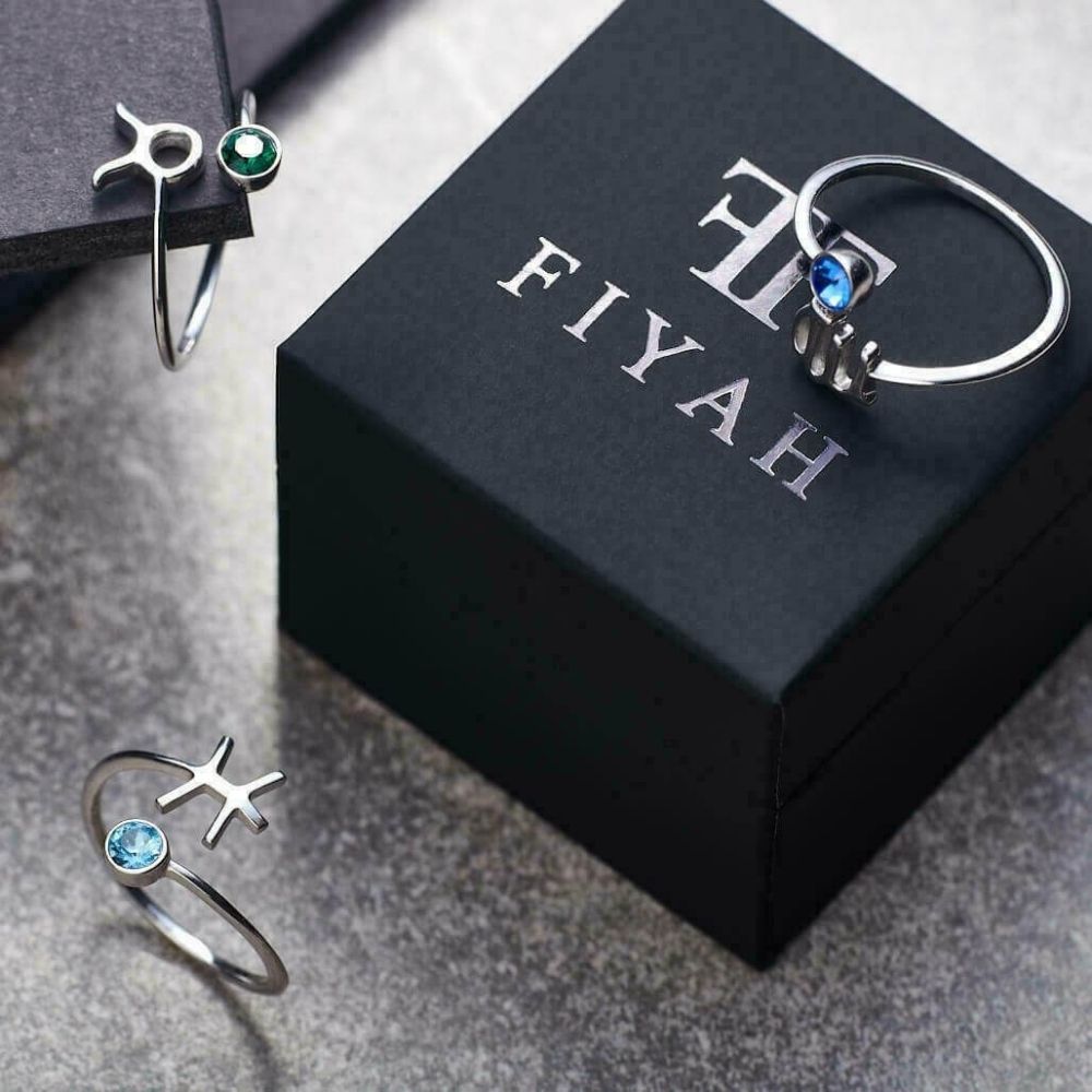 Three silver adjustable rings from the FIYAH Zodiac jewellery collection displayed with a FIYAH ring gift box