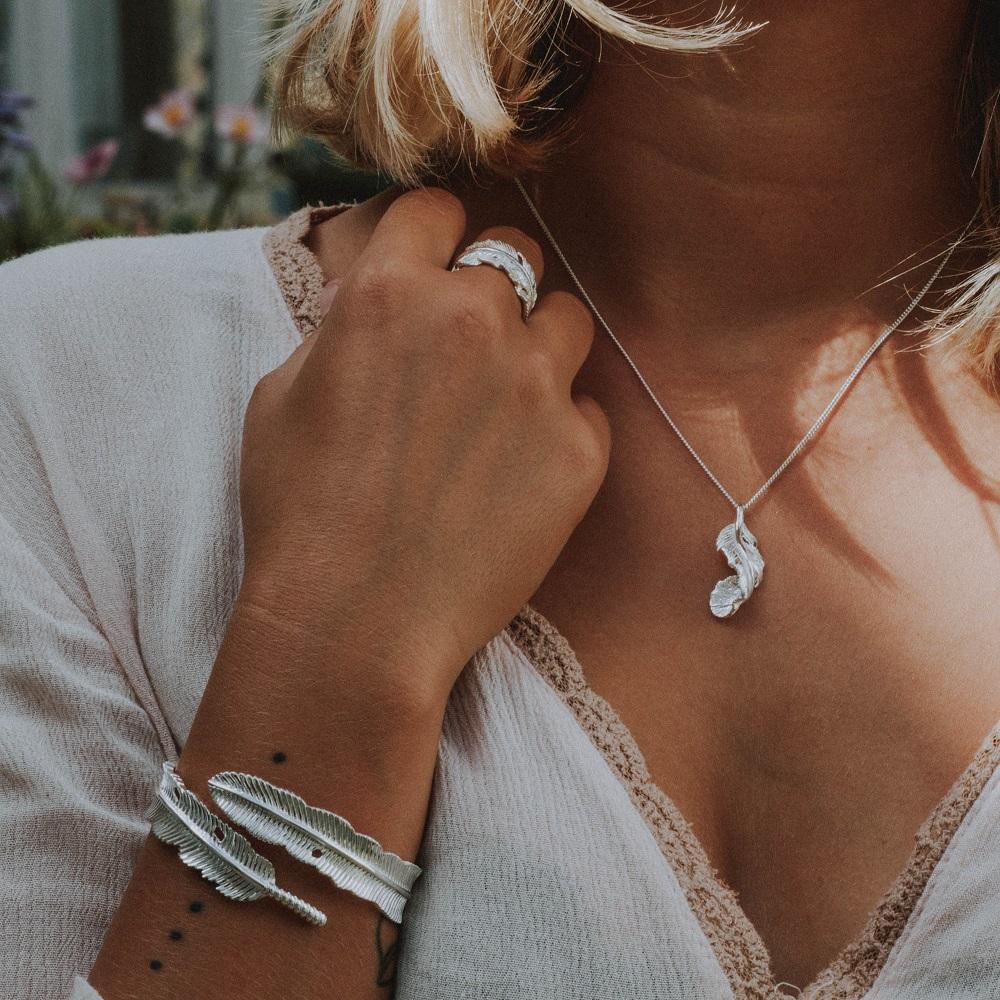 Woman wearing the FIYAH silver imperial plume feather bangle