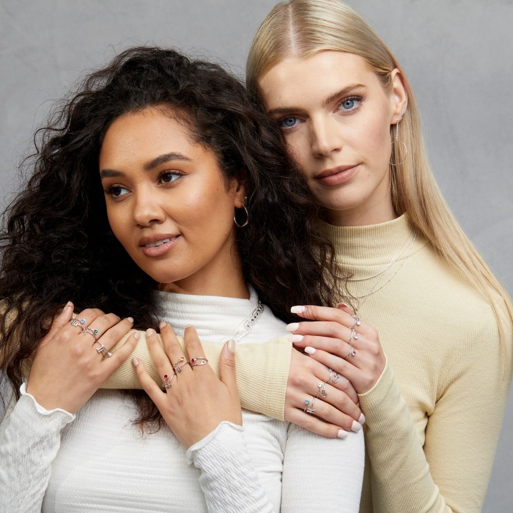 Two women wearing all zodiac rings for the FIYAH zodiac jewellery collection