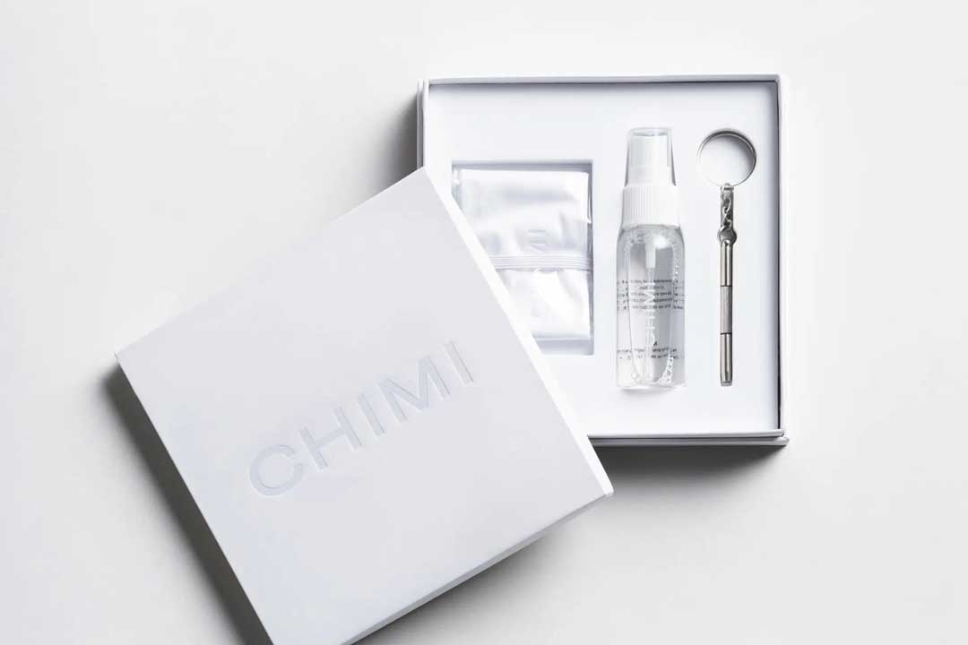 A white gift box containing glasses cleaning spray bottle and optical screwdriver