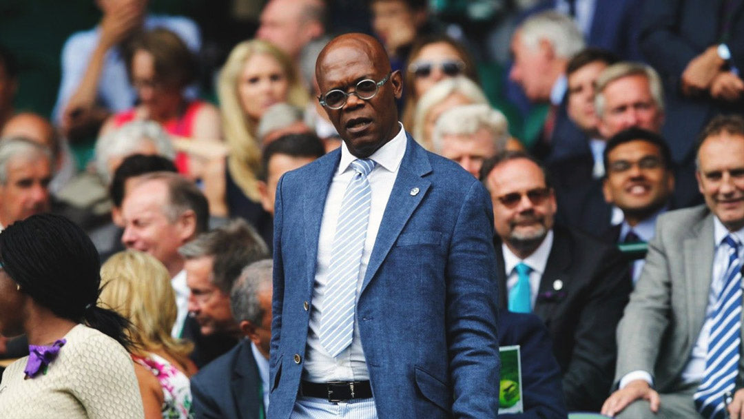 Actor Samuel L Jackson at Wimbledon wearing blue suit and sunglasses standing up in the crowd