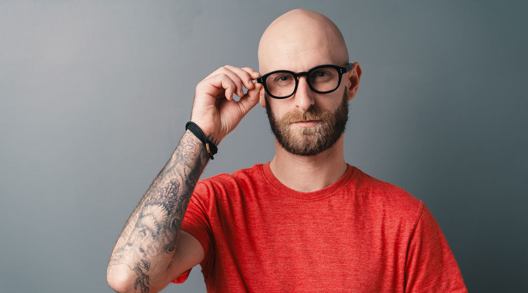 Bald man putting on black glasses frame