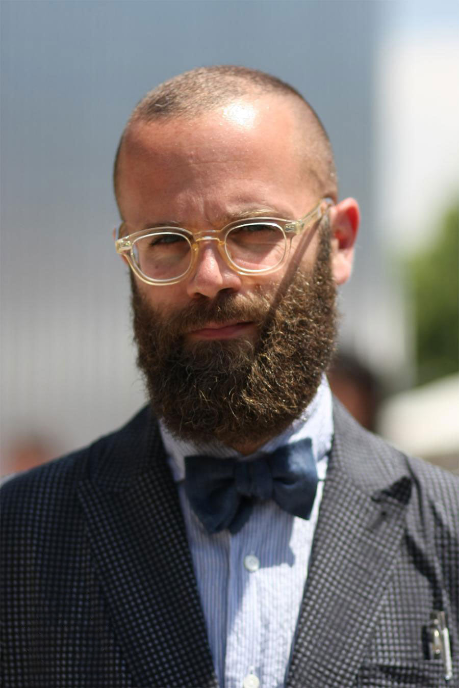 Bearded bald man wearing semi opaque thick glasses frame