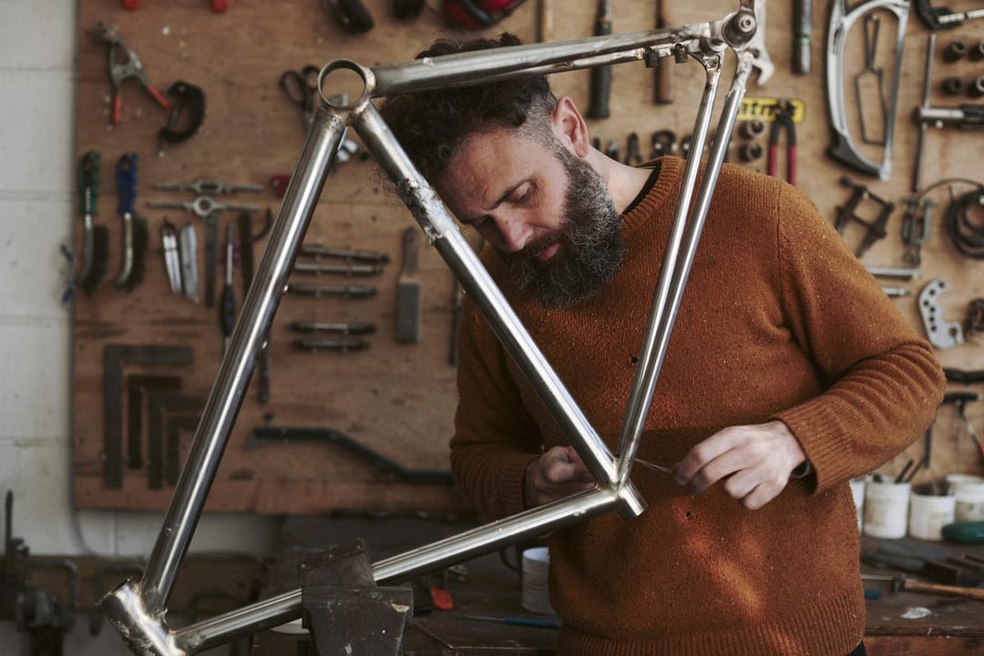 Bearded man in workshop making a steel bicycle frame