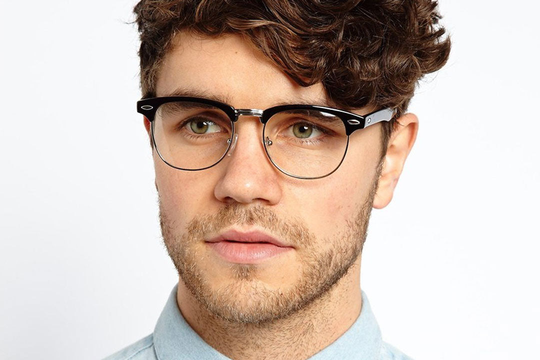 Bearded young man wearing blue shirt and black and silver clubmaster eyeglasses