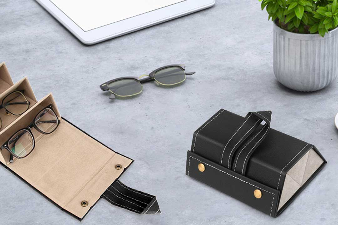 Black leather sunglasses travel case lying on grey table