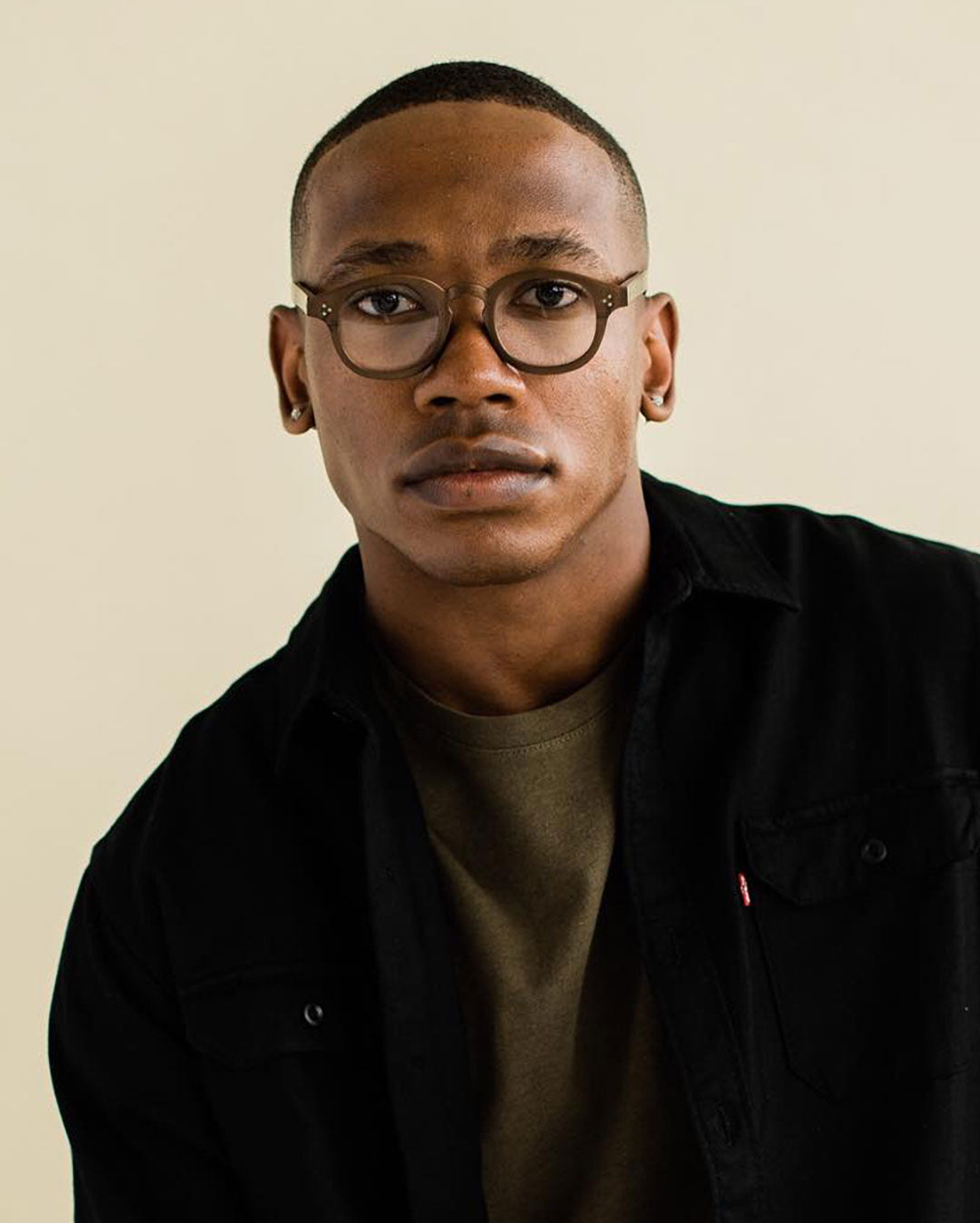 Black male wearing thick rimmed recycled plastic spectacles looking directly at viewer
