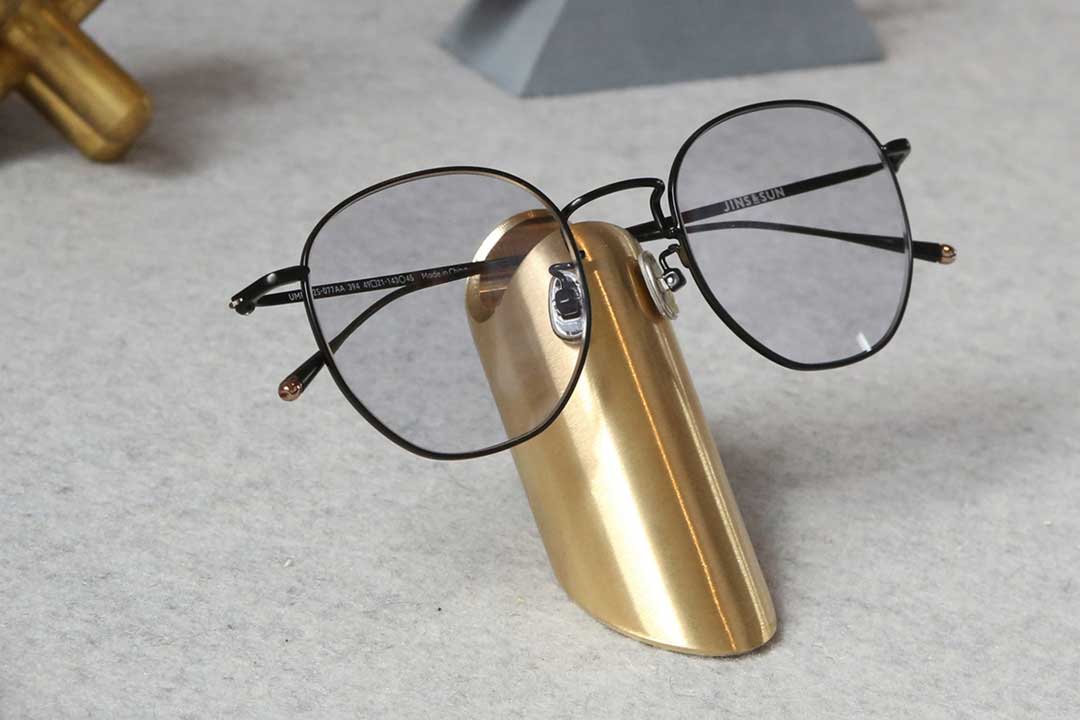 Black wire rim eyeglasses resting on metal glasses stand