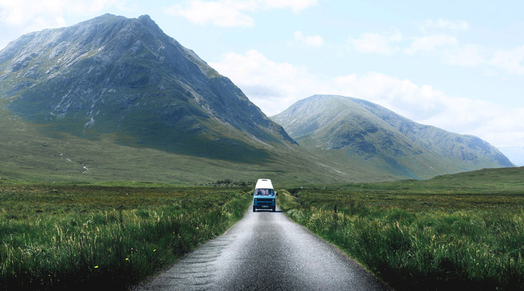 Blue VW camper van driving along rural road