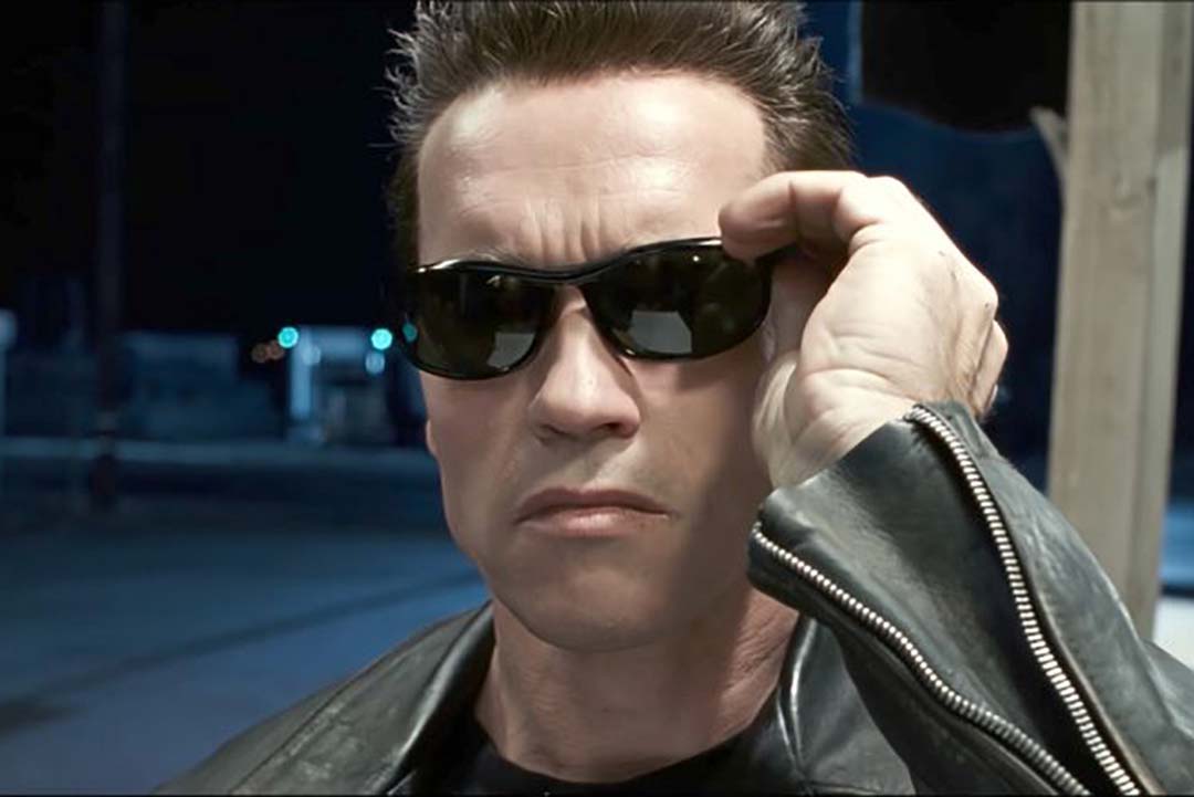 Close view of Arnold Schwarzenegger putting on dark black sunglasses frame