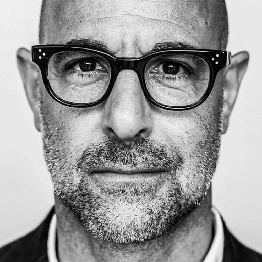 Close view of Stanley Tucci wearing thick rimmed eyeglasses