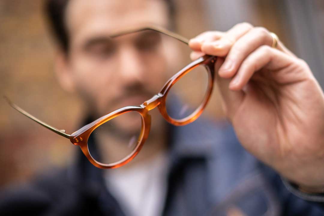 Close view of person holding round amber eyeglasses frame