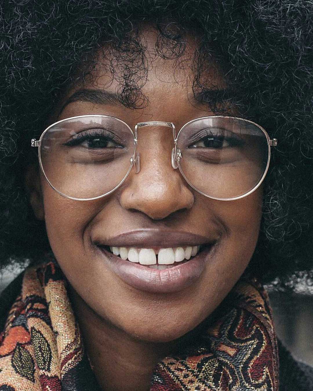 Close view of woman smiling wearing round wire spectacles