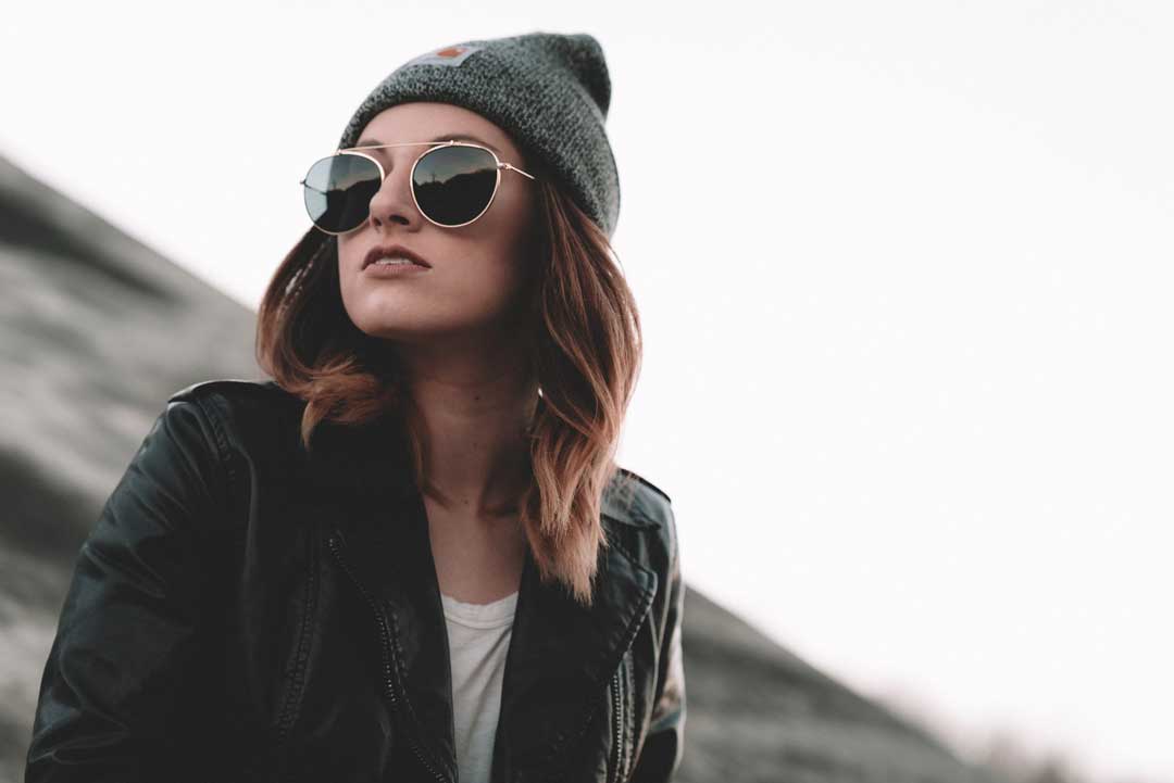 Close view of woman wearing wire rimmed sunglasses hat and jacket