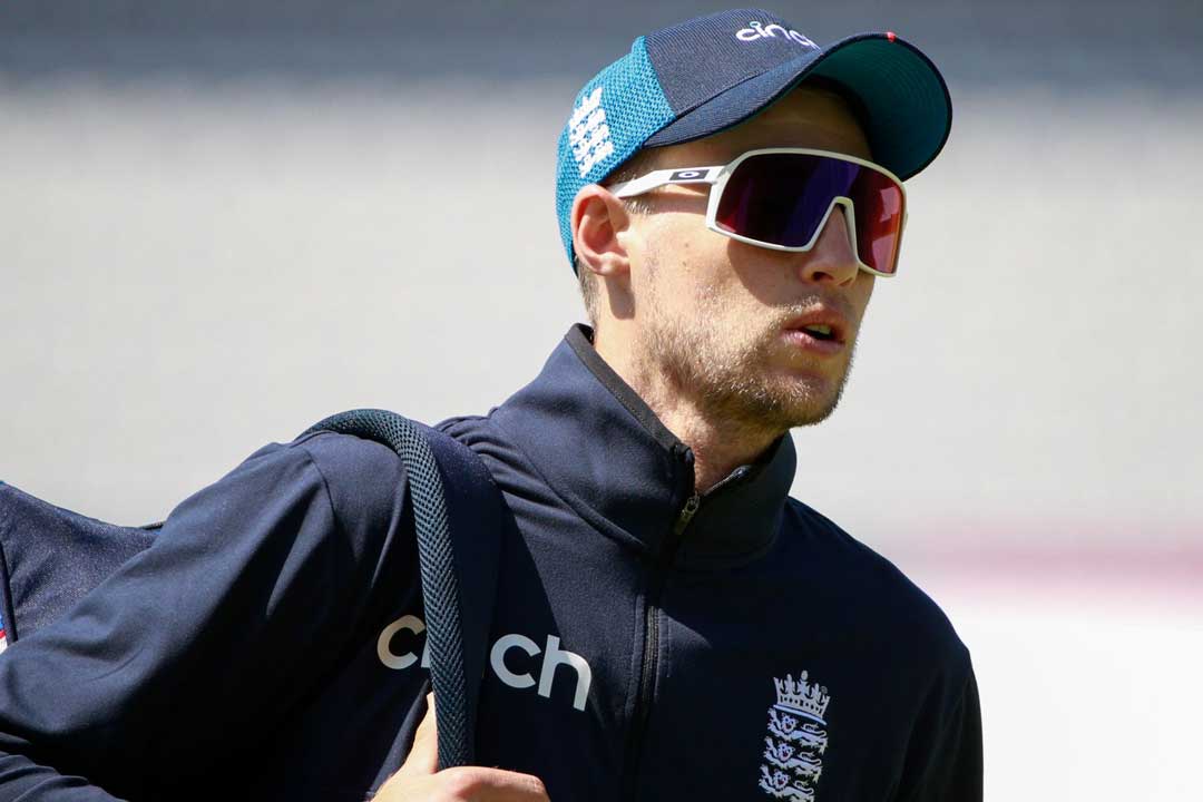 Cricket player Joe Root carrying sports bag wearing blue cap and large white sports sunglasses frame