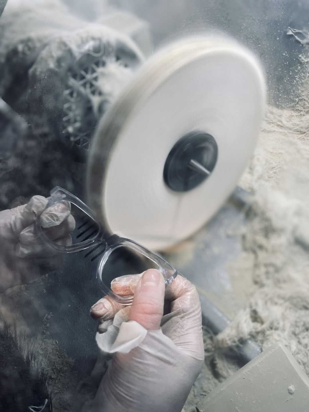 Detail view of a worker hand polishing a sunglasses frame on polishing wheel