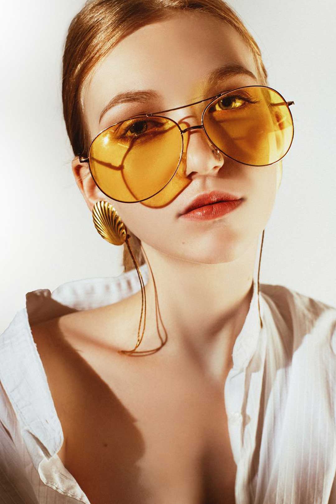 Ginger haired lady wearing very large wire Aviator eyeglasses with lightly tinted orange lenses