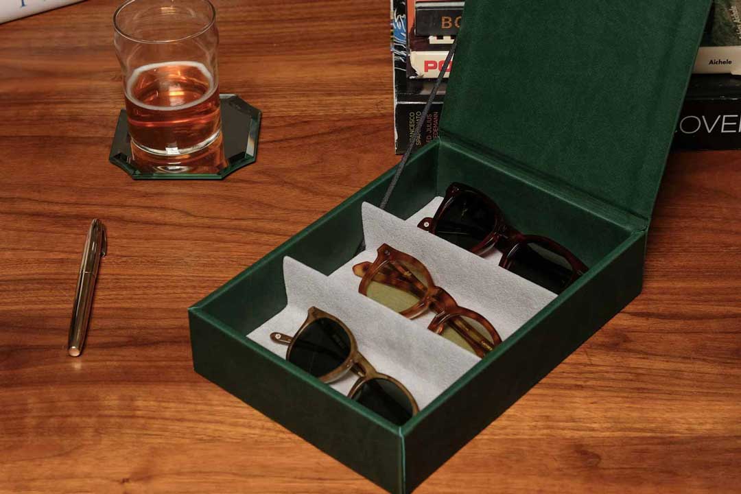 Green leather sunglasses box lying on wood writing table