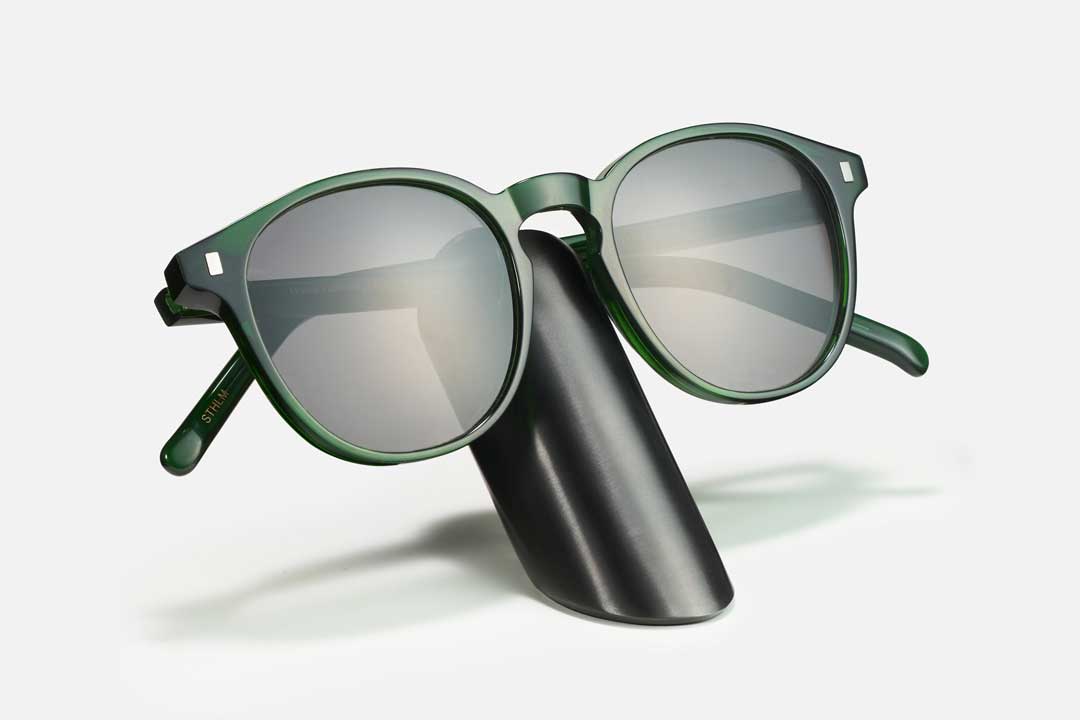 Green rimmed sunglasses frame on black spectacle plinth