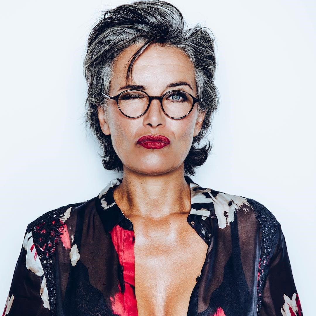 Grey haired women with round tortoise glasses frame and floral blouse